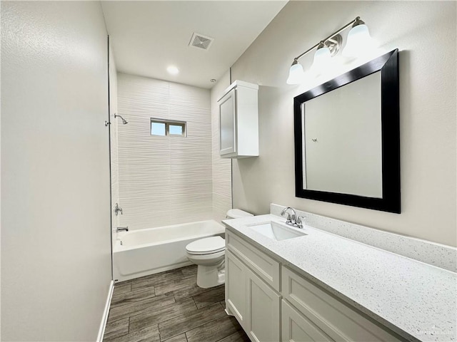 full bathroom featuring vanity, tiled shower / bath combo, and toilet