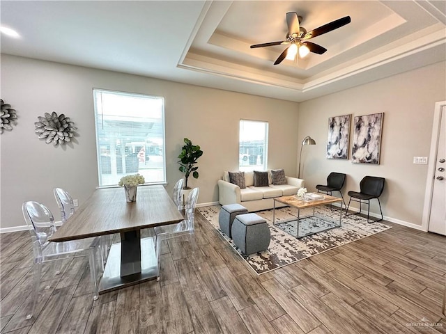 living room featuring wood-type flooring, a raised ceiling, and ceiling fan