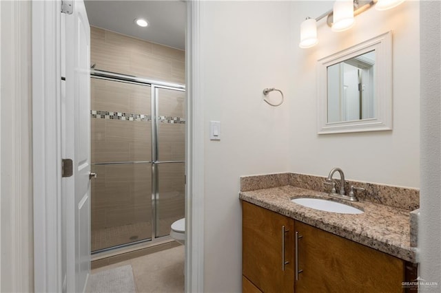 bathroom featuring tile patterned flooring, vanity, a shower with shower door, and toilet