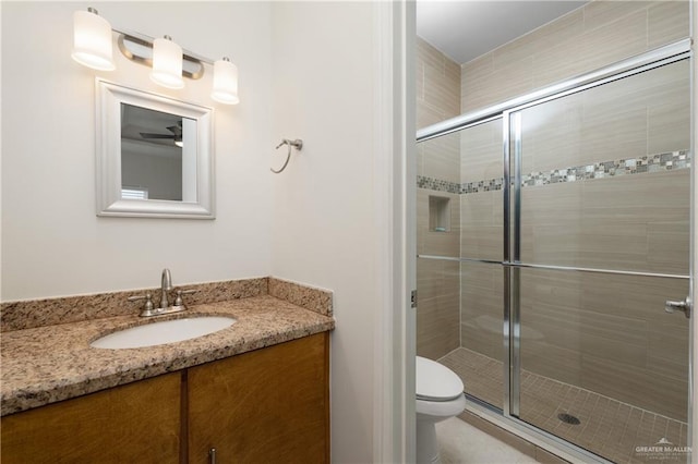 bathroom with vanity, ceiling fan, toilet, and a shower with door