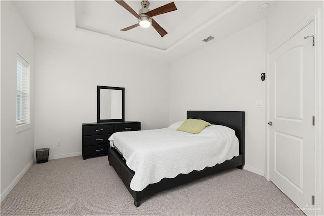 bedroom featuring a tray ceiling, ceiling fan, and light colored carpet