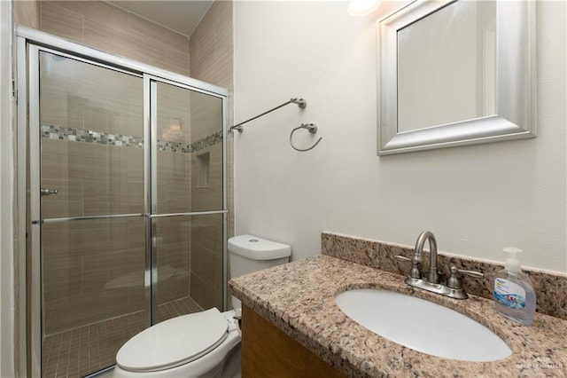 bathroom featuring vanity, toilet, and a shower with shower door