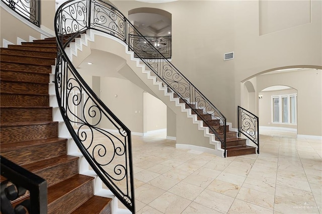 stairs featuring a towering ceiling and a healthy amount of sunlight