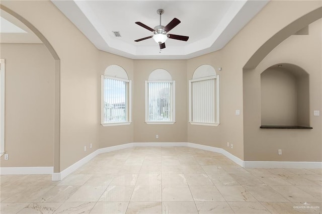 empty room featuring ceiling fan and a tray ceiling