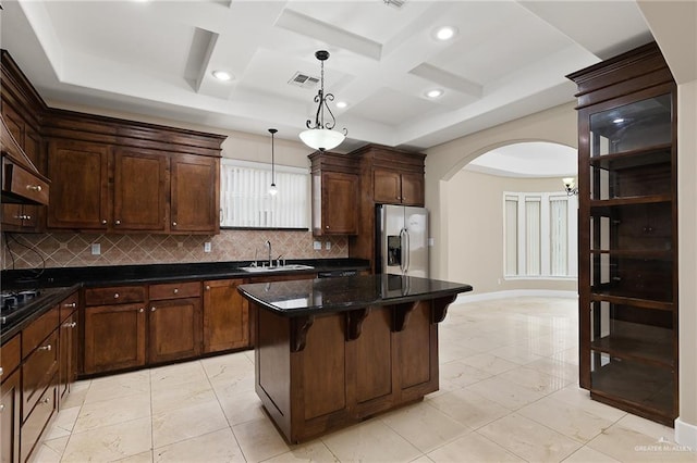 kitchen with sink, stainless steel fridge, coffered ceiling, a kitchen island, and decorative light fixtures