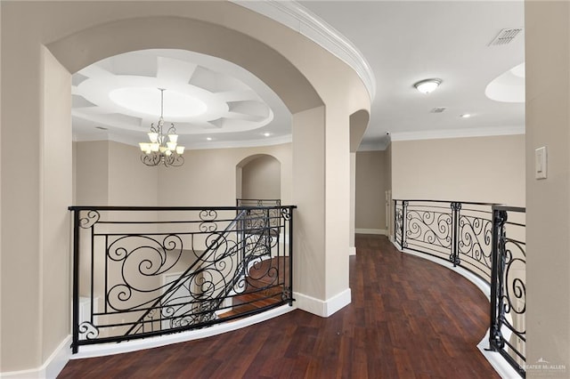 hallway featuring wood-type flooring, ornamental molding, and an inviting chandelier