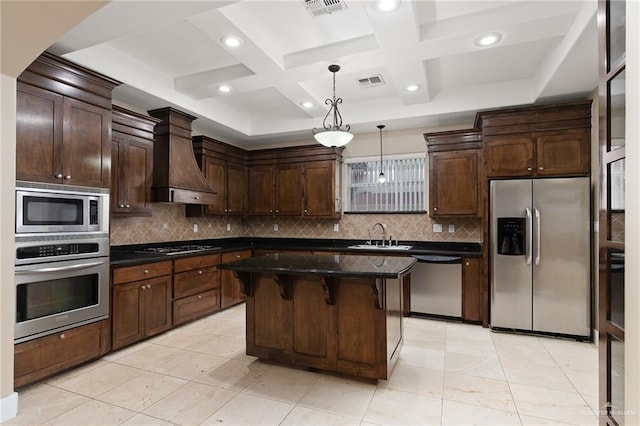 kitchen featuring a breakfast bar area, hanging light fixtures, a kitchen island, custom range hood, and stainless steel appliances