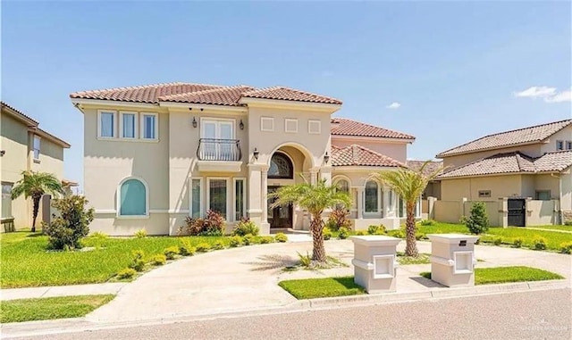 mediterranean / spanish home featuring a balcony and a front lawn