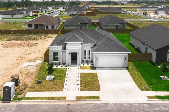 view of front of property with an attached garage, fence, concrete driveway, roof with shingles, and a residential view