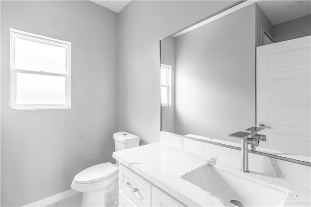 bathroom featuring toilet, baseboards, and vanity