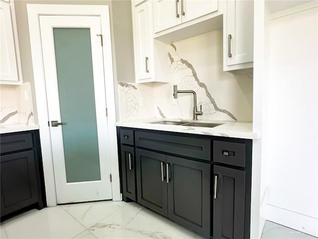 kitchen with tasteful backsplash, marble finish floor, light countertops, and a sink