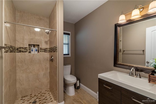 bathroom featuring a tile shower, vanity, and toilet