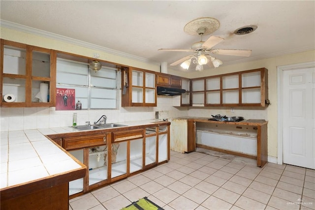 kitchen with backsplash, tile countertops, ceiling fan, and crown molding