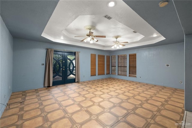 unfurnished room with french doors, a raised ceiling, and ceiling fan