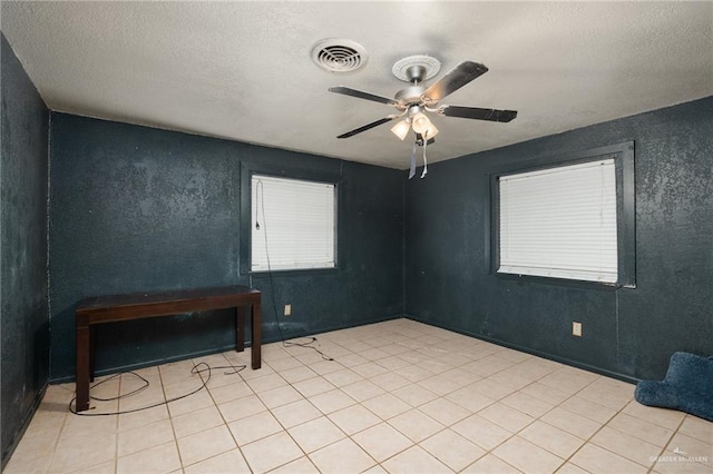 unfurnished room featuring ceiling fan, light tile patterned flooring, and a textured ceiling