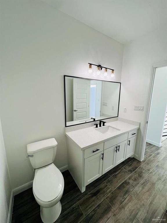 bathroom with hardwood / wood-style flooring, vanity, and toilet