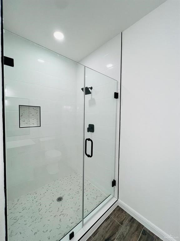 bathroom with a shower with shower door and hardwood / wood-style floors