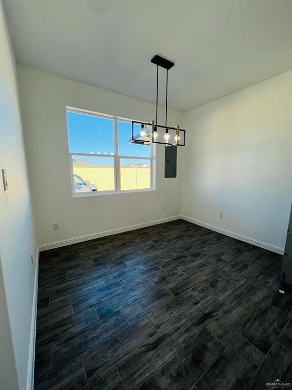 unfurnished dining area featuring an inviting chandelier, dark wood-type flooring, and electric panel