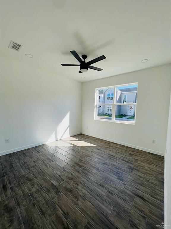 spare room with dark wood-type flooring and ceiling fan