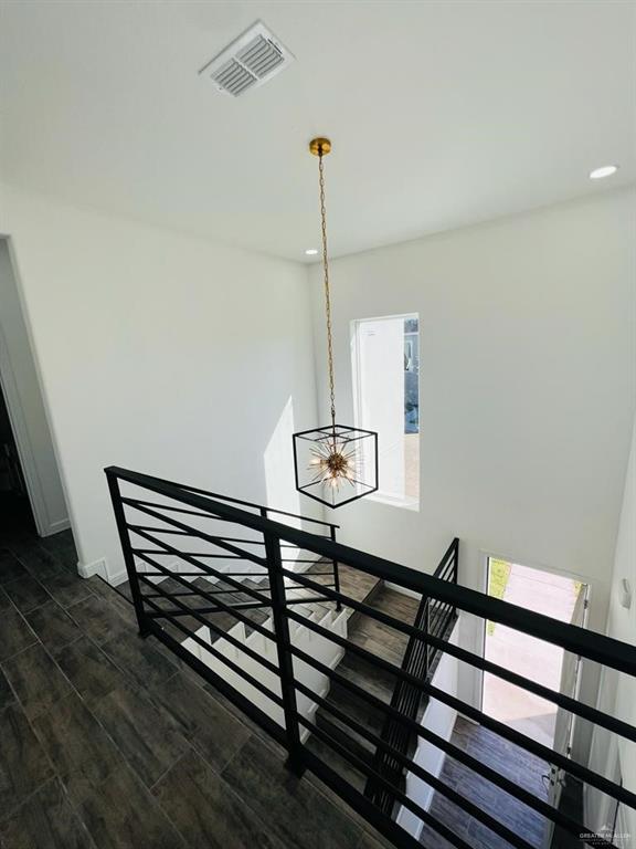 staircase with hardwood / wood-style floors and a notable chandelier