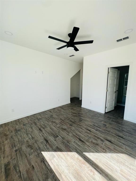 empty room featuring dark wood-type flooring and ceiling fan