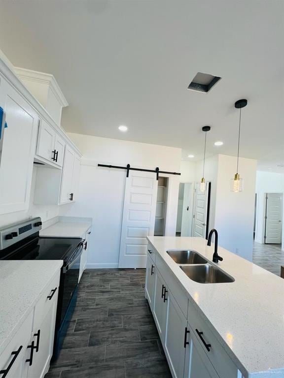 kitchen featuring sink, white cabinetry, light stone counters, electric range, and a barn door