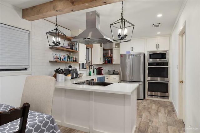 kitchen featuring decorative backsplash, appliances with stainless steel finishes, island range hood, light hardwood / wood-style flooring, and white cabinetry