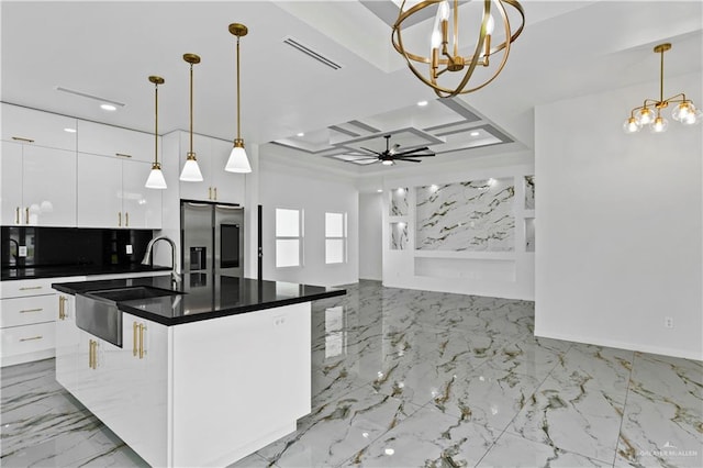 kitchen with stainless steel fridge with ice dispenser, decorative light fixtures, white cabinetry, and a kitchen island with sink