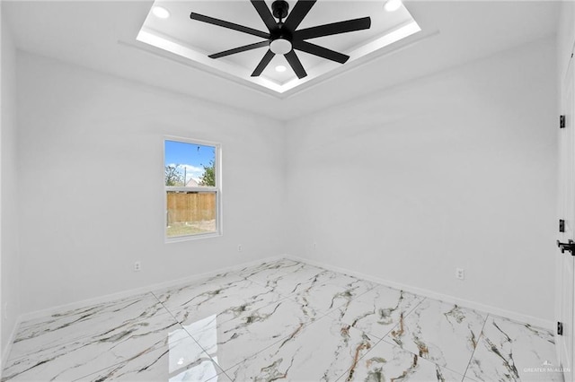 empty room featuring a tray ceiling and ceiling fan