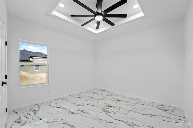 empty room with ceiling fan and a raised ceiling