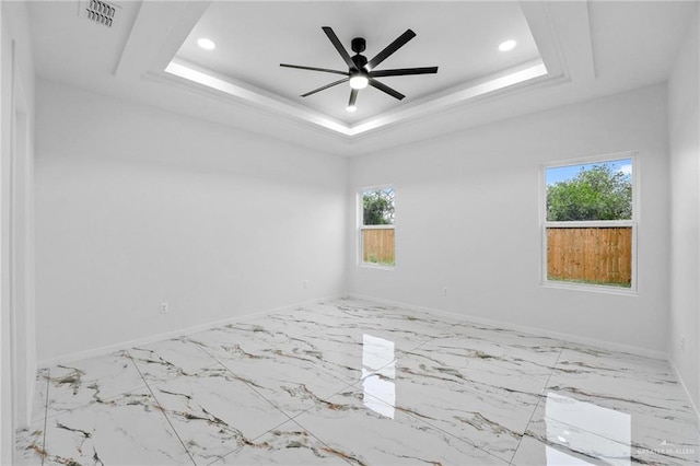 unfurnished room featuring a tray ceiling, ceiling fan, and a healthy amount of sunlight