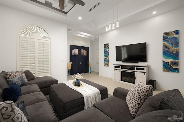 living area featuring baseboards, a glass covered fireplace, visible vents, and recessed lighting