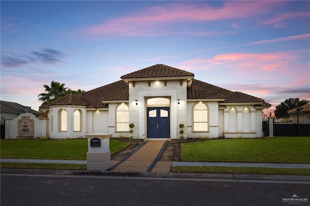 mediterranean / spanish home with a tiled roof, a front yard, fence, and stucco siding