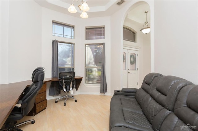 office area featuring a notable chandelier, wood-type flooring, and a tray ceiling