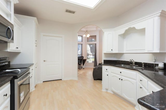 kitchen featuring appliances with stainless steel finishes, sink, a notable chandelier, white cabinets, and light hardwood / wood-style floors