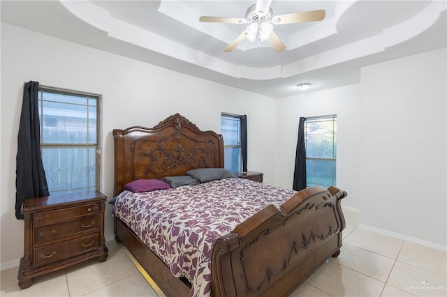 tiled bedroom with a tray ceiling and ceiling fan