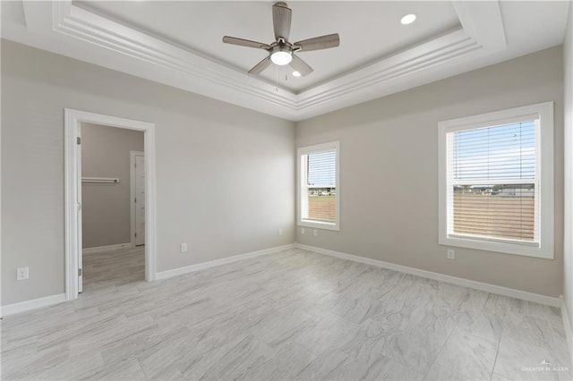 empty room featuring a raised ceiling, a wealth of natural light, and ceiling fan