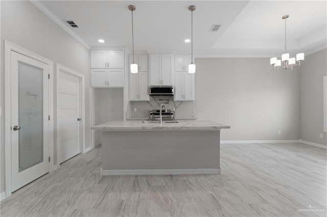 kitchen featuring appliances with stainless steel finishes, light stone counters, pendant lighting, a center island with sink, and white cabinets