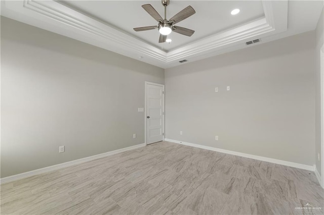 empty room featuring a raised ceiling and ceiling fan