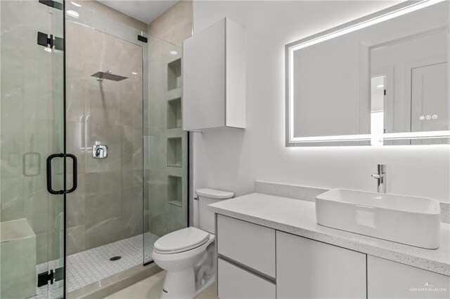 full bath featuring toilet, a stall shower, and vanity