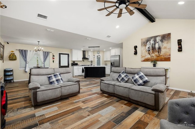 living room with ceiling fan with notable chandelier, vaulted ceiling with beams, hardwood / wood-style flooring, and sink