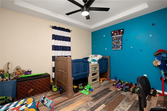 bedroom featuring hardwood / wood-style floors, a tray ceiling, and ceiling fan