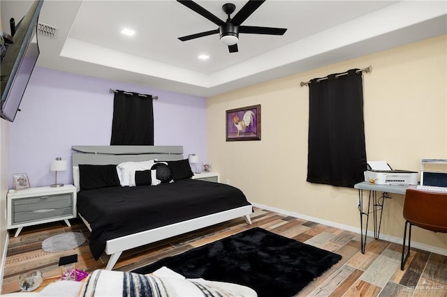 bedroom with a tray ceiling, ceiling fan, and hardwood / wood-style flooring