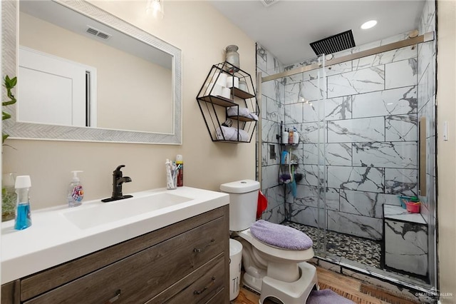 bathroom with hardwood / wood-style flooring, vanity, toilet, and a shower with shower door