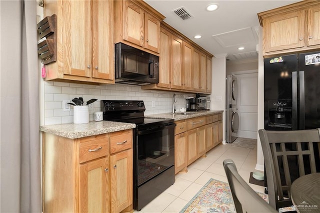 2203 Kingfisher Ln, Mission, TX 78572 - kitchen featuring black appliances, stacked washer and clothes dryer, a sink, light tile patterned floors, and decorative backsplash