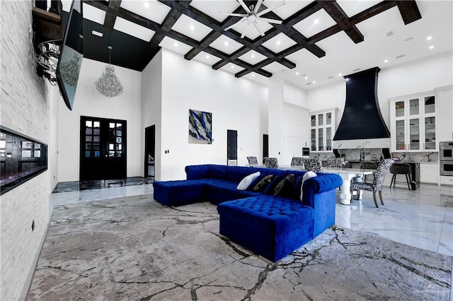 living room featuring ceiling fan, french doors, coffered ceiling, a high ceiling, and beamed ceiling