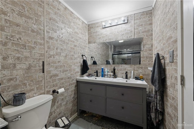 15668 Primera Rd, Harlingen, TX 78552 - full bathroom featuring toilet, double vanity, crown molding, brick wall, and a shower
