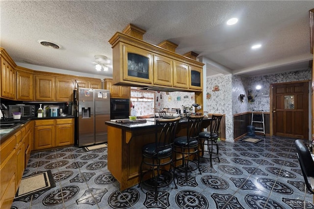 15668 Primera Rd, Harlingen, TX 78552 - kitchen with stainless steel fridge with ice dispenser, a textured ceiling, dark countertops, brown cabinets, and glass insert cabinets
