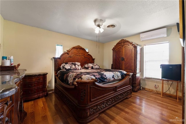 15668 Primera Rd, Harlingen, TX 78552 - bedroom featuring a wall unit AC, wood finished floors, baseboards, a ceiling fan, and a textured ceiling