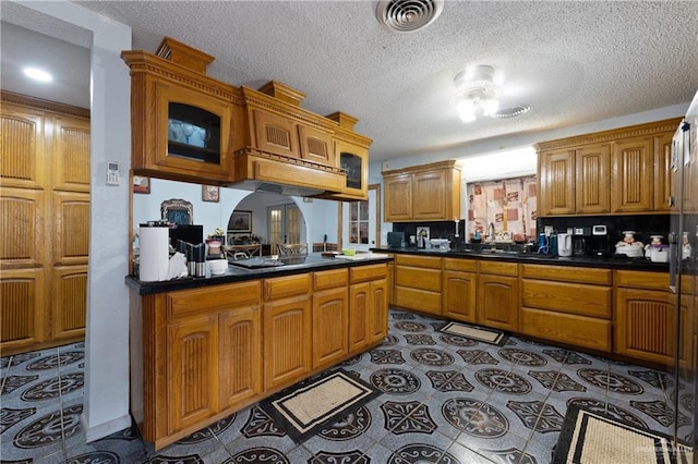 15668 Primera Rd, Harlingen, TX 78552 - kitchen with brown cabinets, dark countertops, a textured ceiling, tile patterned flooring, and black electric cooktop